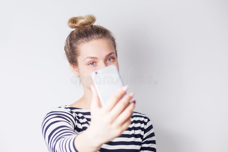 Closeupstående av den härliga attraktiva le blonda kvinnan som tar selfie på smartphonen på vit royaltyfri foto Closeupstående av den härliga attraktiva le blonda kvinnan som tar selfie på smartphonen på vit royaltyfri foto