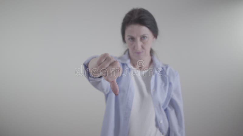 Closeuse de la main femelle montrant pouce vers le bas. femme caucasienne floue gesturant non en secouant la tête à l'arrière-plan clips vidéos