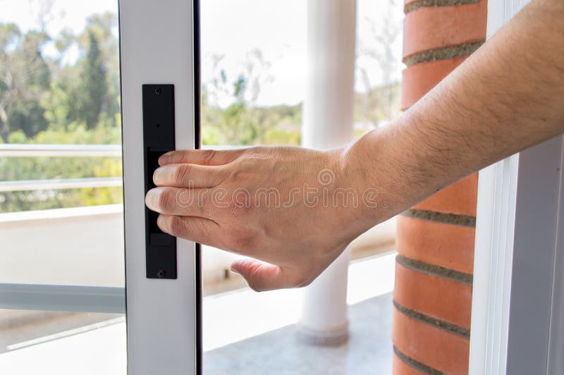 Detail of hand close the aluminum door of the balcony. Detail of hand close the aluminum door of the balcony