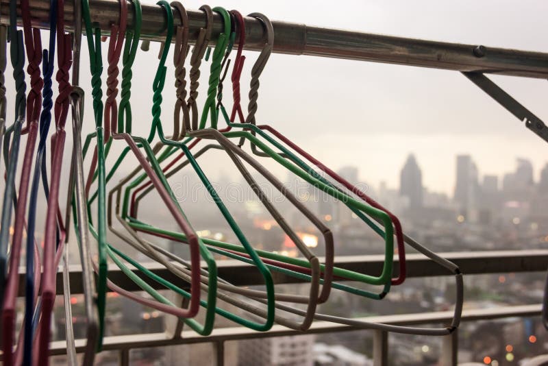 Cloth hangers on Cloth Line at the balcony of residential building in a rainy day with blurry city view background, cannot wash