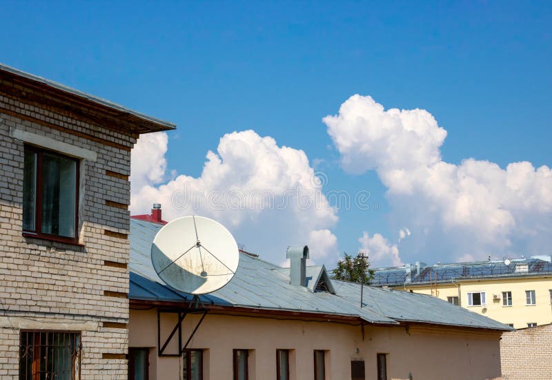 Clouds and a TV antenna. white satellite dish on the roof.