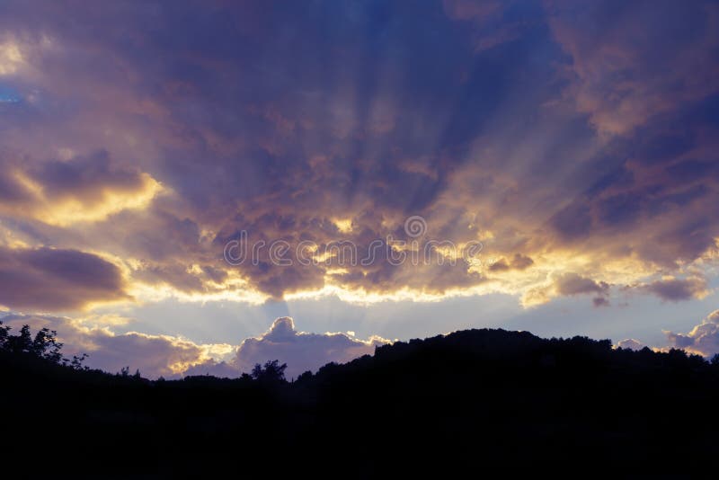 Cloudscape celeste drammatico al tramonto ed alla siluetta di hillrange. Cloudscape celeste drammatico al tramonto dei colori gialli e porpora con hillrange qui sotto