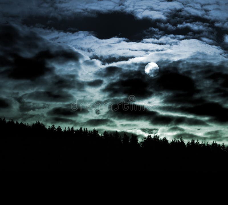 Scenic view of full moon illuminating dramatic cloudscape at night over silhouetted forest. Scenic view of full moon illuminating dramatic cloudscape at night over silhouetted forest.