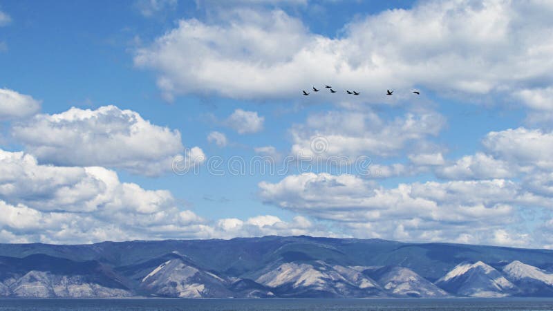 Cloudy sky on the background of the mountain coast with a flock of birds flying in the heaven. royalty free stock photo Cloudy sky on the background of the mountain coast with a flock of birds flying in the heaven. royalty free stock photo