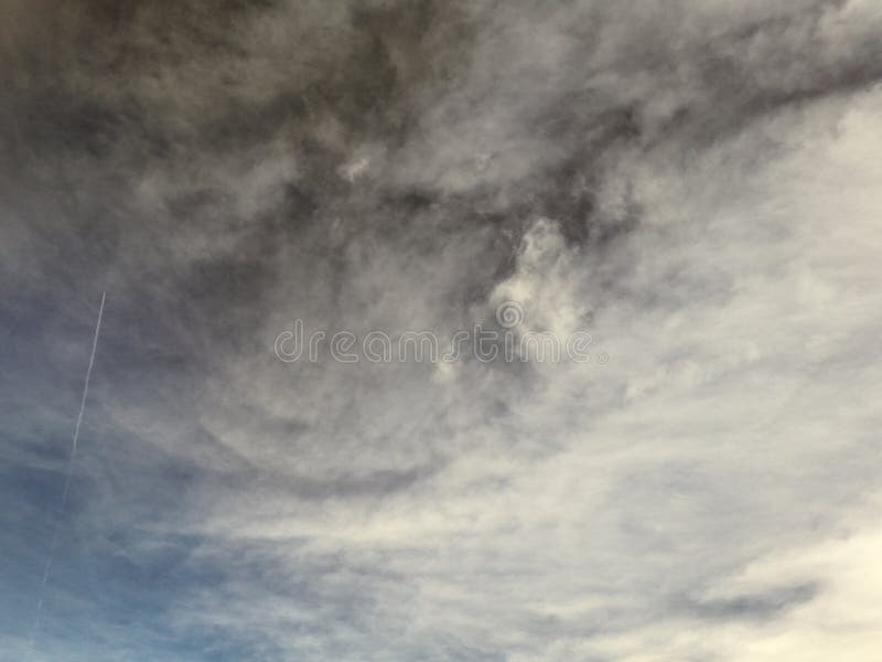 Cloudy sky with a mix of dark and light clouds, creating a dramatic atmosphere. The sun is partially hidden, casting a soft glow. A reflection of an indoor light is visible on the screen.
