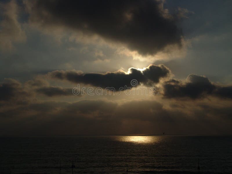 Cloudy sunset over a beach with a circle of light over the ocean water stock image Cloudy sunset over a beach with a circle of light over the ocean water stock image