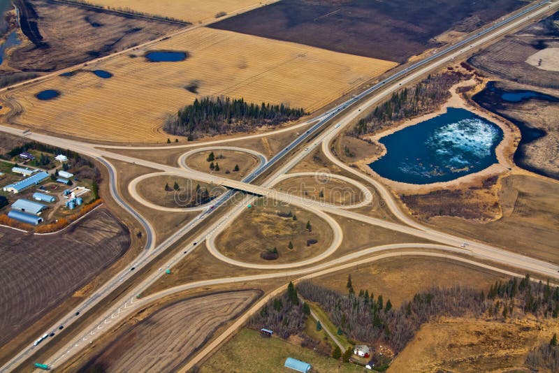 An aerial view of a highway joining another highway in a cloverleaf pattern. An aerial view of a highway joining another highway in a cloverleaf pattern