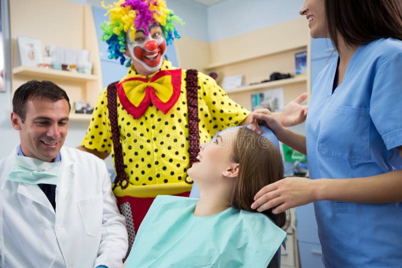 Clownen i tand- klinik gör skrattunga flickan royaltyfri foto Clownen i tand- klinik gör skrattunga flickan royaltyfri foto