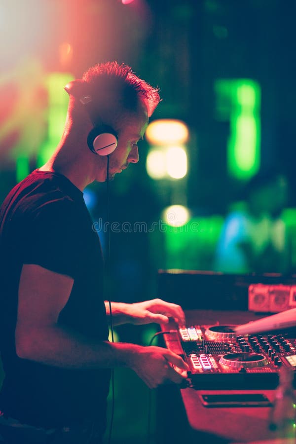 Club, disco DJ playing and mixing music for crowd of happy people. Nightlife, concert lights, flares. stock photography Club, disco DJ playing and mixing music for crowd of happy people. Nightlife, concert lights, flares. stock photography