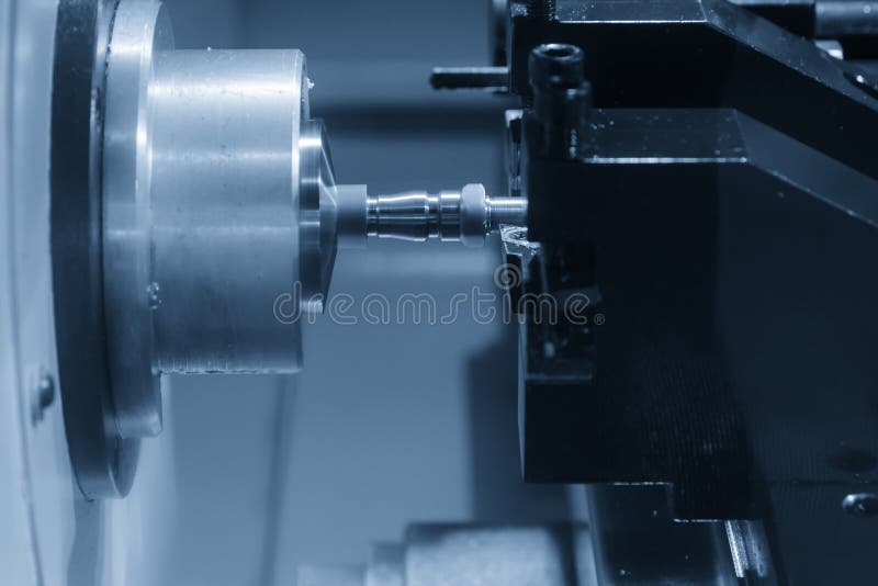 The CNC lathe machine in metal working process cutting the screw and nut parts with the cutting tools.
