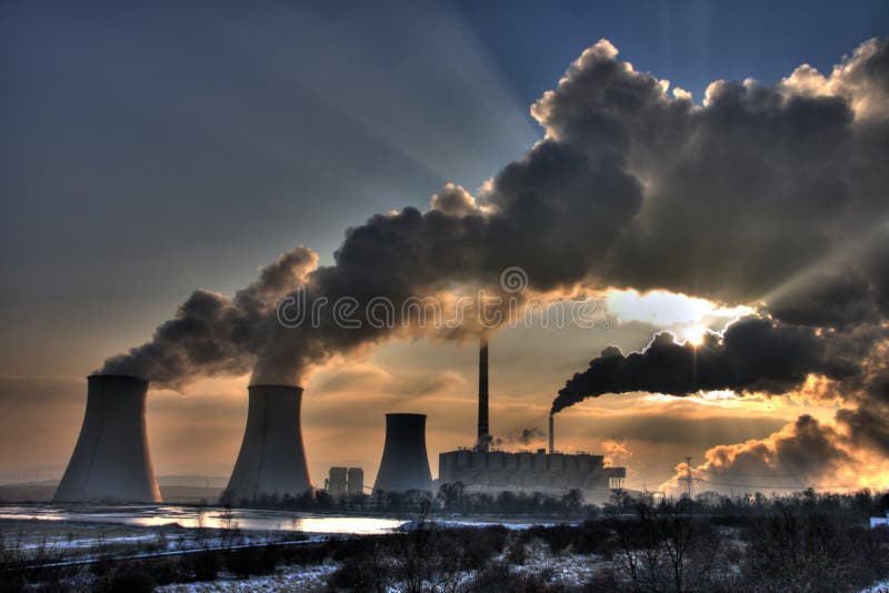 Vista di carbone del gruppo motopropulsore contro il sole con parecchi camini e grande fumi.