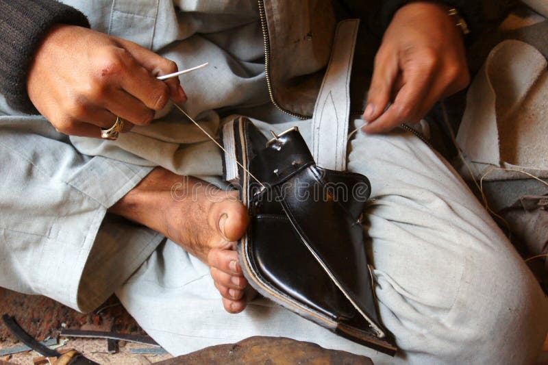 A Asian Cobbler stitching a traditional shoe near Peshawar.