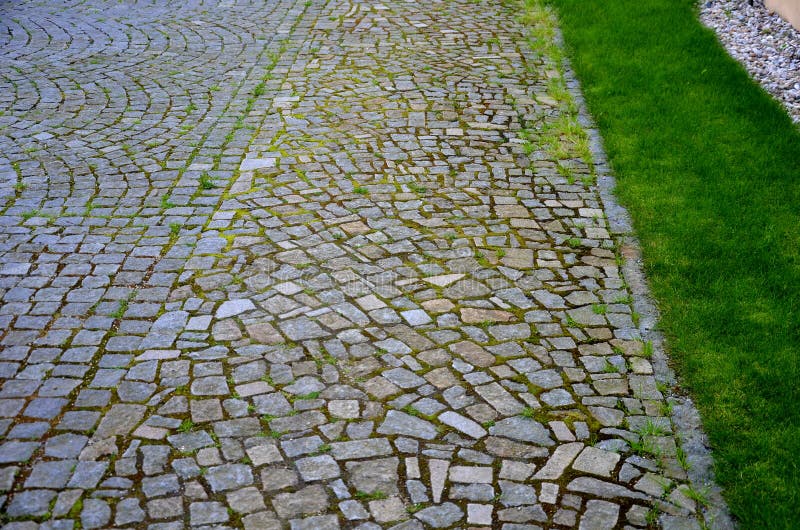 Stone path lined with regular granite cubes the center of the path is made of irregular granite sections around the lawn park park