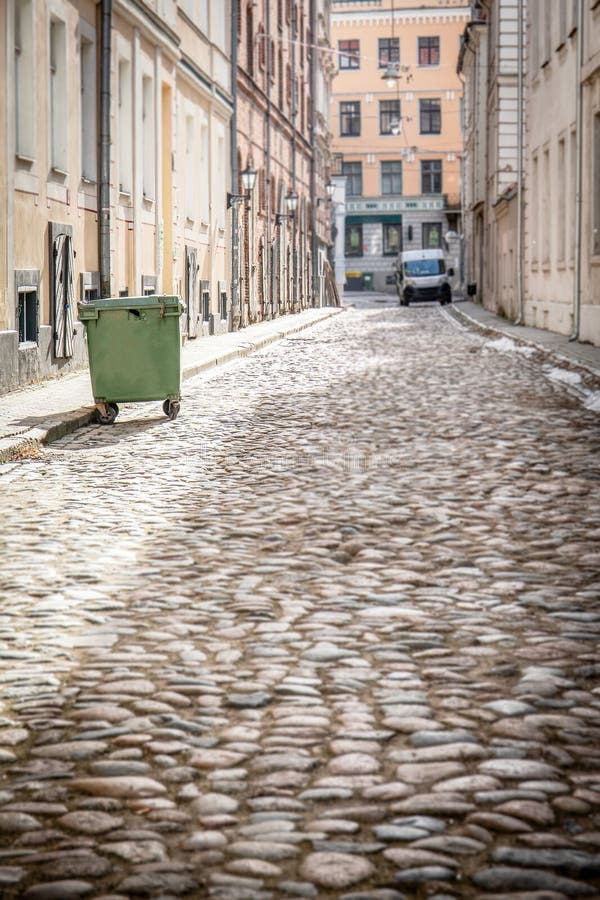 Cobblestone Street with Green Trash Bin and Historic Buildings stock images