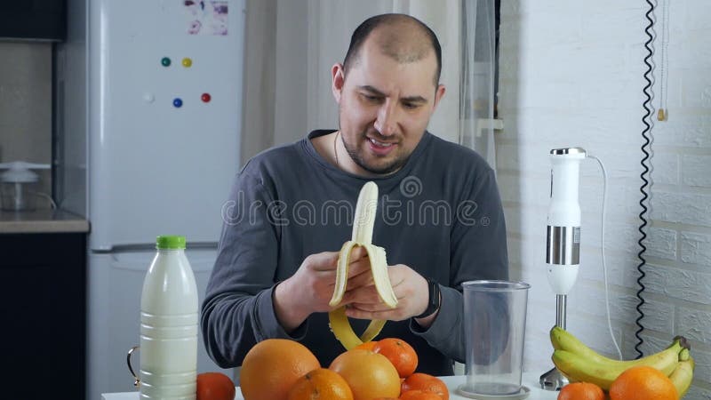 Cocción de un batido de plátano. manos mens pelar un plátano maduro y colocarlo en una licuadora para hacer una fruta vegana salud almacen de metraje de vídeo