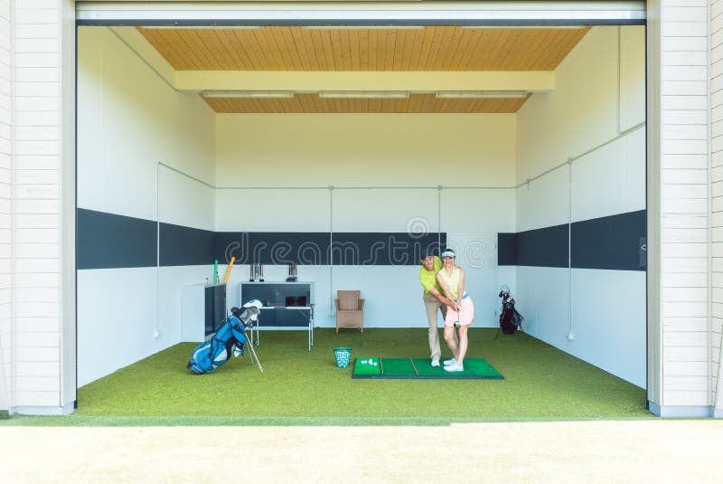 Coche dedicado del golf usando el equipo moderno mientras que enseña a una mujer joven