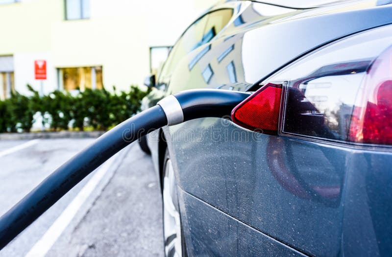 Coche eléctrico de carga con el negro que carga el cable eléctrico tapado fotografía de archivo Coche eléctrico de carga con el negro que carga el cable eléctrico tapado fotografía de archivo