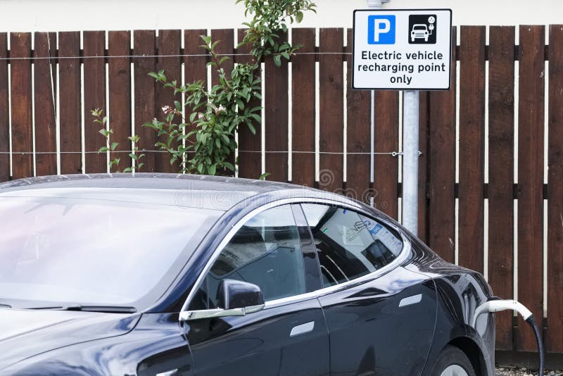 Coche eléctrico de Tesla que carga en zona de estacionamiento imagen de archivo libre de regalías Coche eléctrico de Tesla que carga en zona de estacionamiento imagen de archivo libre de regalías