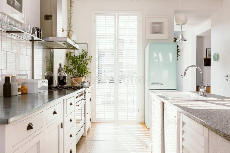 Cocina luminosa con muebles modernos de color blanco frigorífico de menta pastel y gran ventanal