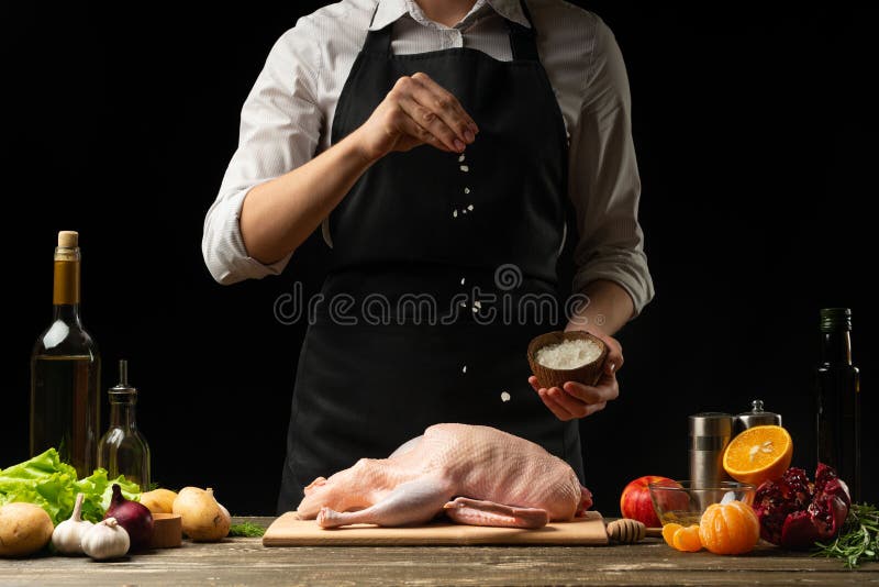 Cooking a festive duck for the Christmas, New Year`s Eve dinner chef.Preparing fresh duck. Horizontal photo with dark black background,. Cooking a festive duck for the Christmas, New Year`s Eve dinner chef.Preparing fresh duck. Horizontal photo with dark black background,