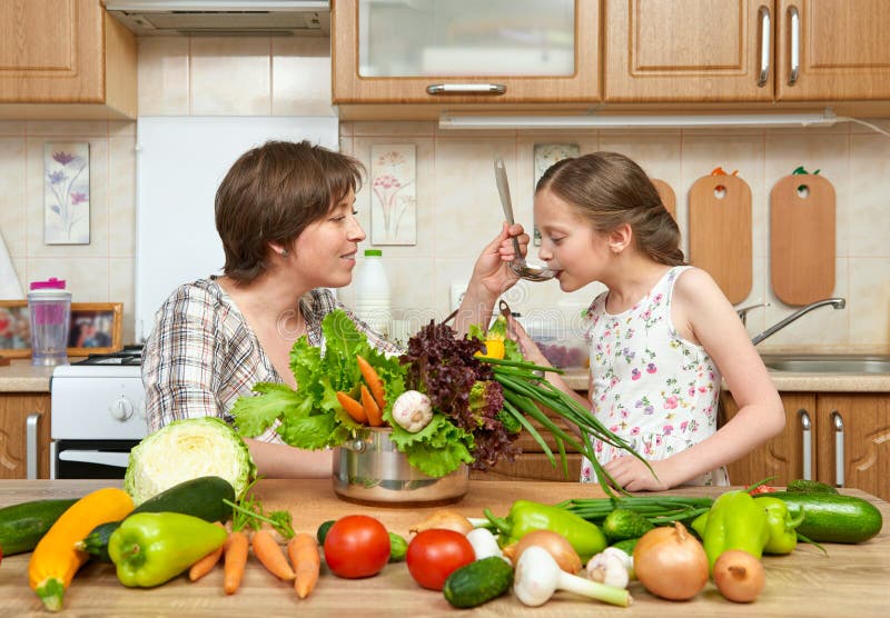 Cocinero de la madre y de la hija y sopa del gusto de verduras Interior casero de la cocina Padre y niño, mujer y muchacha Estafa