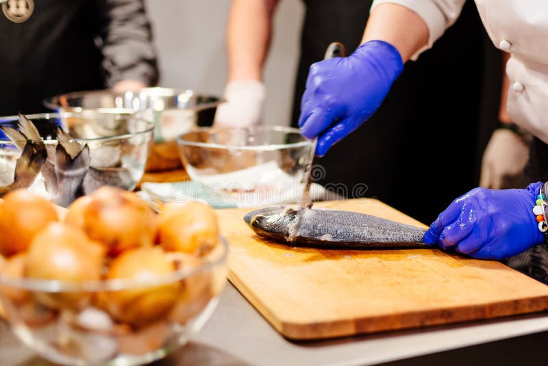 Cocinero de la mujer que prepara y que limpia pescados crudos del dorada fotos de archivo Cocinero de la mujer que prepara y que limpia pescados crudos del dorada fotos de archivo