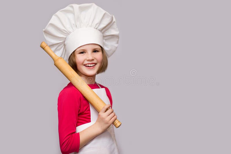 Cocinero de los niños Niña feliz en el rodillo uniforme de los controles del cocinero aislado en el fondo blanco imagenes de archivo