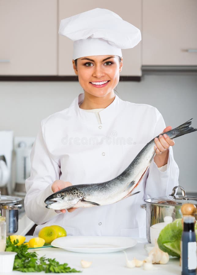 Cocinero de sexo femenino que prepara pescados grandes fotos de archivo libres de regalías Cocinero de sexo femenino que prepara pescados grandes fotos de archivo libres de regalías
