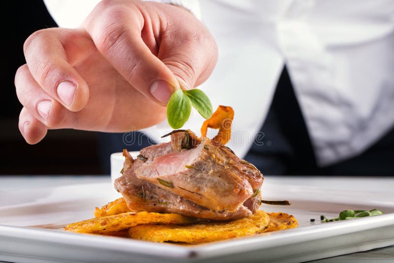 Cocinero en cocina del hotel o del restaurante que cocina, solamente manos Filete preparado de la carne con las crepes de la pata