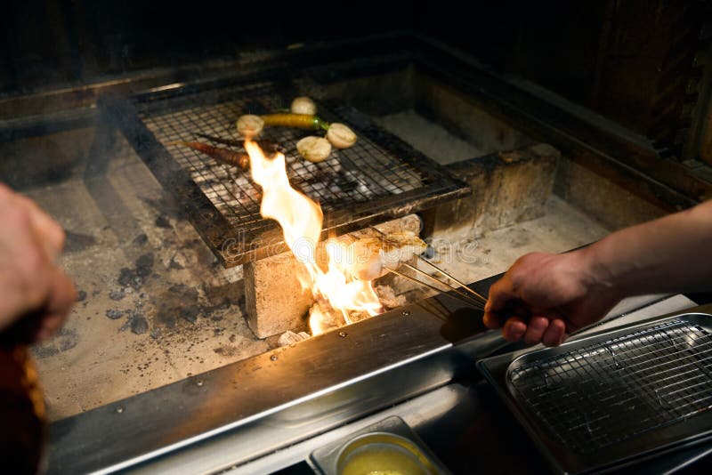 Cocinero masculino parcial frito filete de pescado y verduras en chimenea imagen de archivo