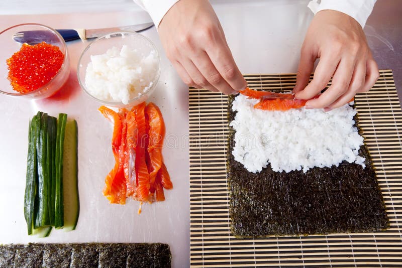 Cocinero que hace los rodillos de sushi japoneses imagen de archivo Cocinero que hace los rodillos de sushi japoneses imagen de archivo