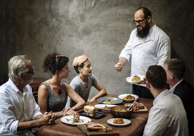Cocinero que presenta la comida a los clientes en el restaurante fotografía de archivo Cocinero que presenta la comida a los clientes en el restaurante fotografía de archivo