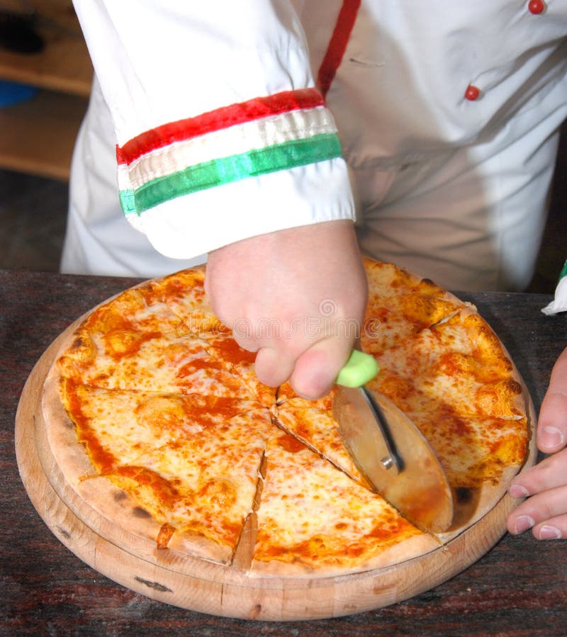 Cocinero que rebana la pizza imágenes de archivo libres de regalías Cocinero que rebana la pizza imágenes de archivo libres de regalías