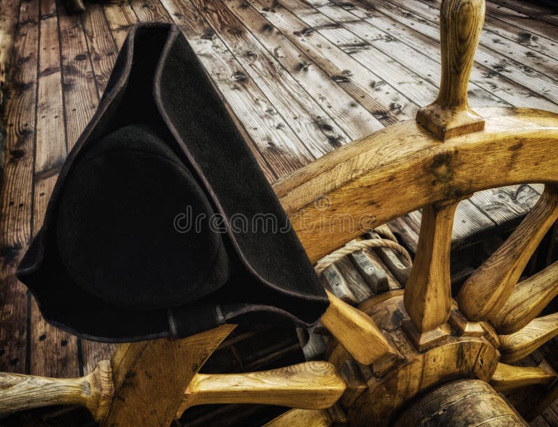 The cocked hat on the old wooden steering wheel of the ship stock photo The cocked hat on the old wooden steering wheel of the ship stock photo