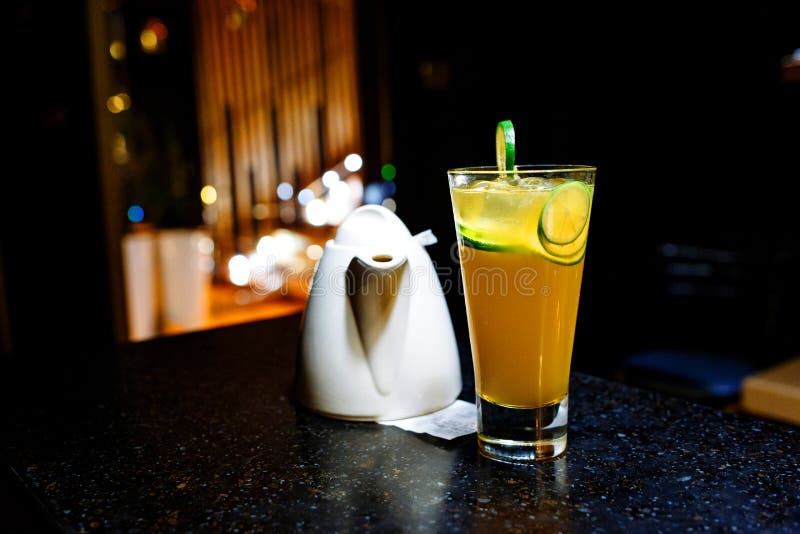 Cocktail arancio con calce e la teiera su fondo scuro immagini stock libere da diritti Cocktail arancio con calce e la teiera su fondo scuro immagini stock libere da diritti