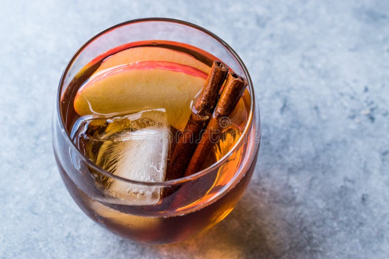 Cocktail de whiskey de cidre d'Apple avec des tranches de bâtons de cannelle, de glace et d'Apple photographie stock Cocktail de whiskey de cidre d'Apple avec des tranches de bâtons de cannelle, de glace et d'Apple photographie stock
