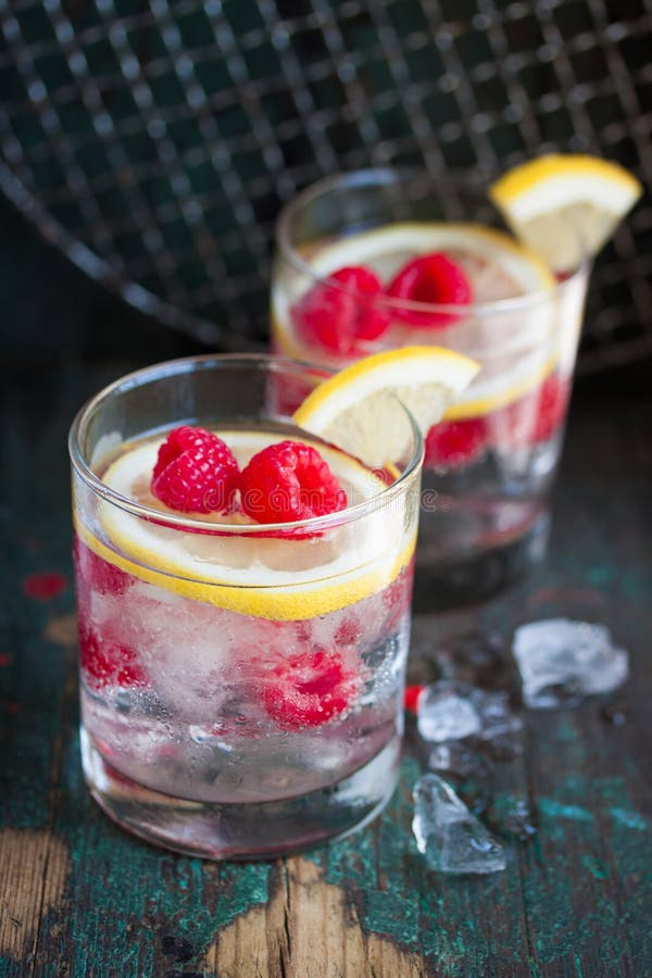 Cocktail freddo del limone del lampone di estate casalinga con acqua frizzante e schiacciato ghiacciato in vetri su un fondo d'an immagini stock Cocktail freddo del limone del lampone di estate casalinga con acqua frizzante e schiacciato ghiacciato in vetri su un fondo d'an immagini stock