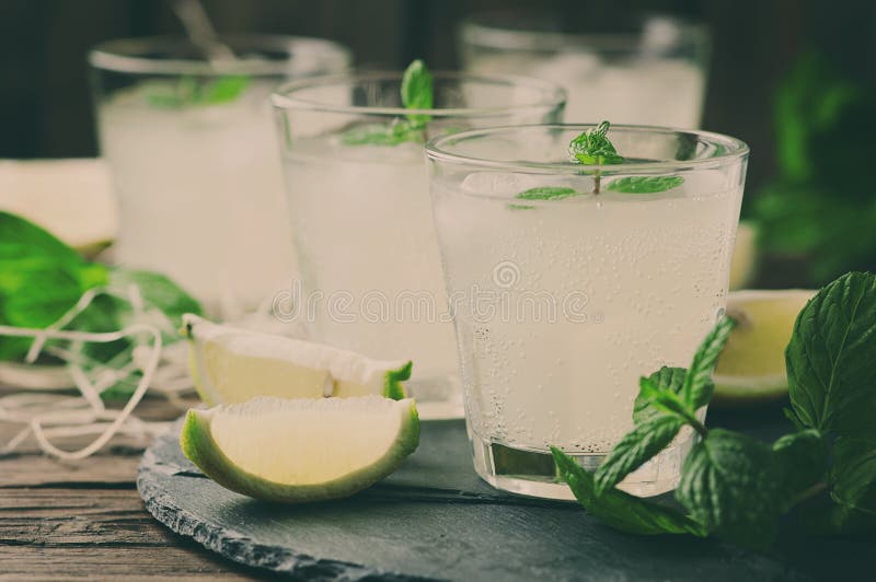 Cocktail fresco con il limone, il ghiaccio e la menta sulla tavola d'annata fotografia stock libera da diritti Cocktail fresco con il limone, il ghiaccio e la menta sulla tavola d'annata fotografia stock libera da diritti
