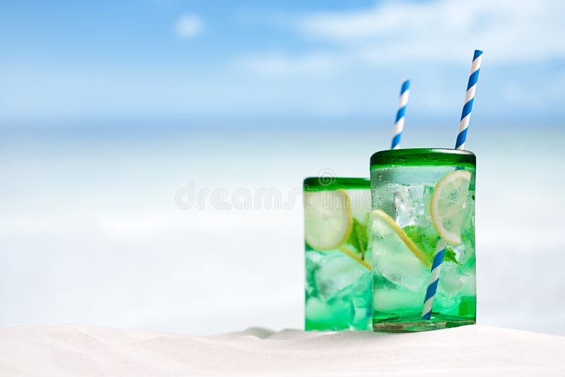 Cocktail with ice, rum, lemon and mint in a glass on beach