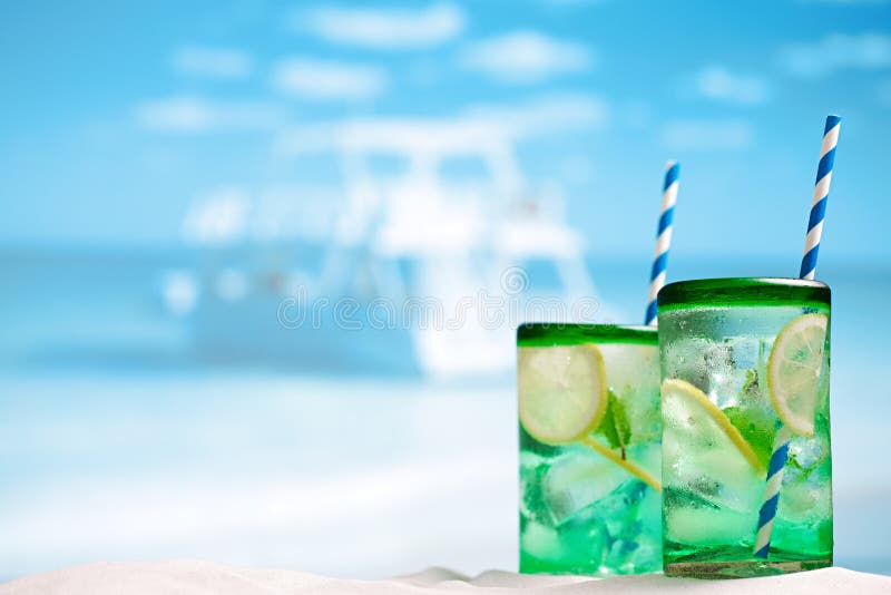 Cocktail with ice, rum, lemon and mint in a glass on beach