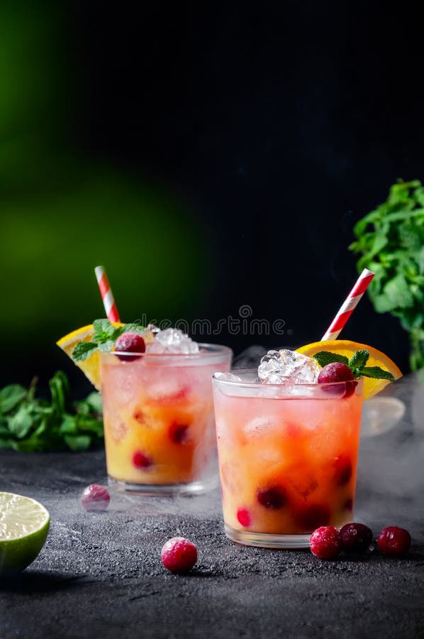 Cocktail mit Rum- oder Wodkasodamoosbeerorangensaftkalk und -minze im Glas mit Rauch auf dunkelgrauem Hintergrund stockbilder