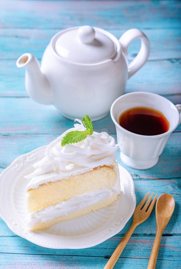 Coconut cake decorated with coconut meat and mint leaf on a white plate, With a tea of ready-to-drink and a teapot placed on a stock photo Coconut cake decorated with coconut meat and mint leaf on a white plate, With a tea of ready-to-drink and a teapot placed on a stock photo