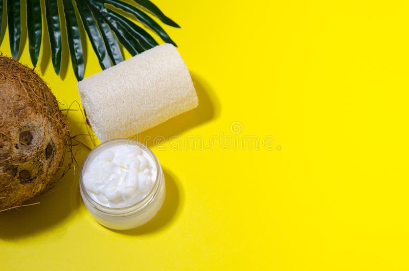 Coconut, cream in an open transparent jar, cream in a white plastic bottle with a dispenser on a palm leaf lay on a yellow background