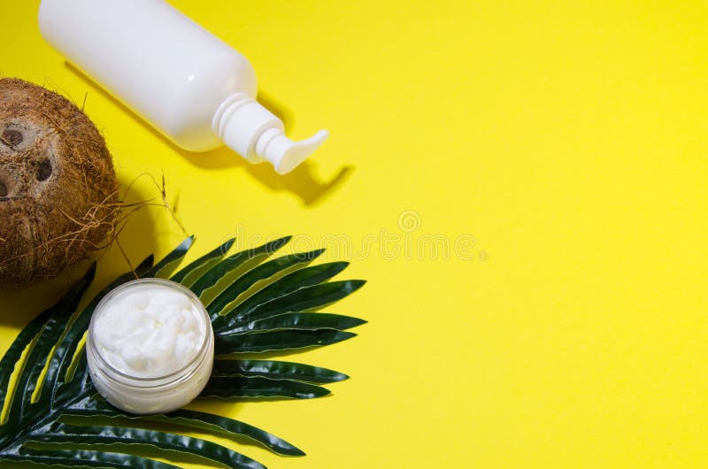 Coconut, cream in an open transparent jar, cream in a white plastic bottle with a dispenser on a palm leaf lay on a yellow background