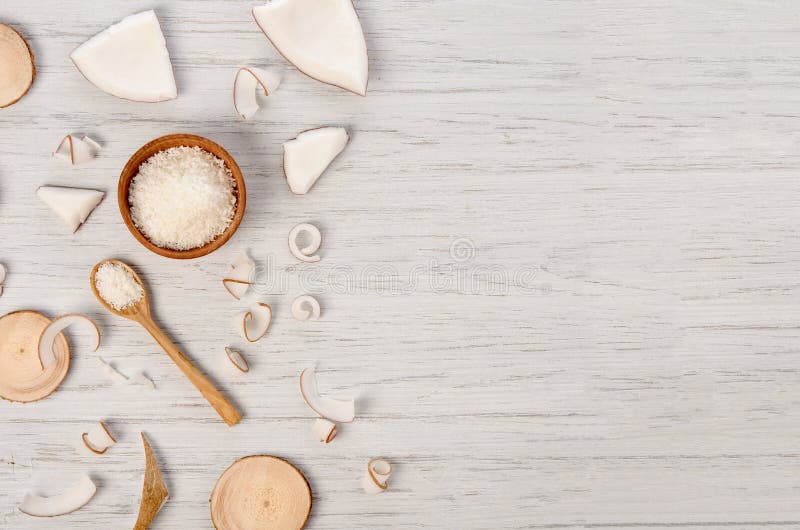 Coconut flesh slices and spiral curl with wooden spoon and circles on white table with copy pace royalty free stock photography Coconut flesh slices and spiral curl with wooden spoon and circles on white table with copy pace royalty free stock photography