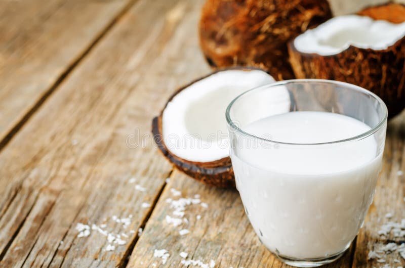 Coconut milk and coconuts. On a dark wood background. the toning. selective focus stock photography