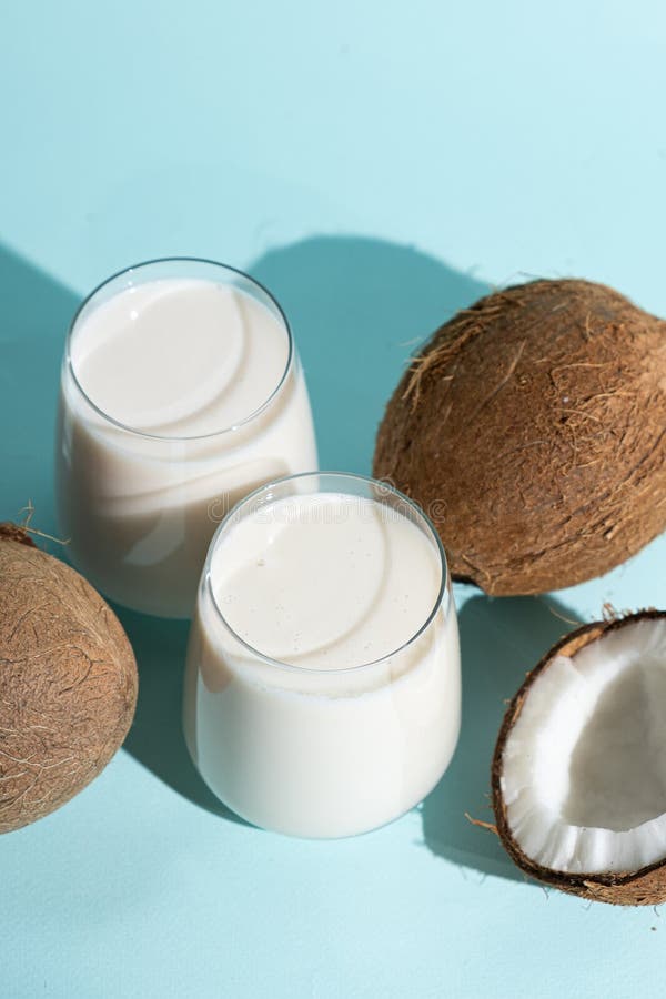 Coconut Milk in a Glasses among Coconuts on a Blue Background Stock