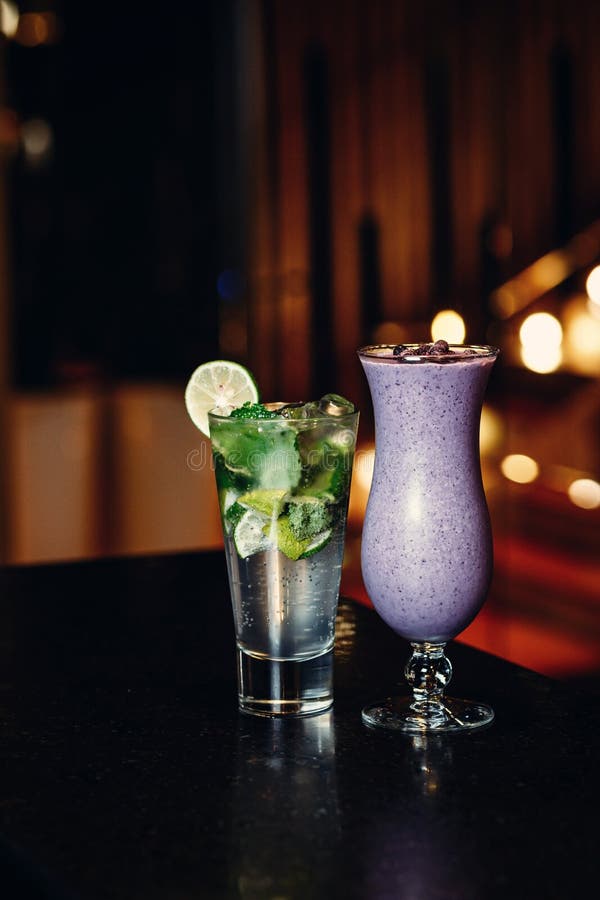 Coctailar på den svarta tabellen - mojito- och bärsmoothie arkivfoton Coctailar på den svarta tabellen - mojito- och bärsmoothie arkivfoton