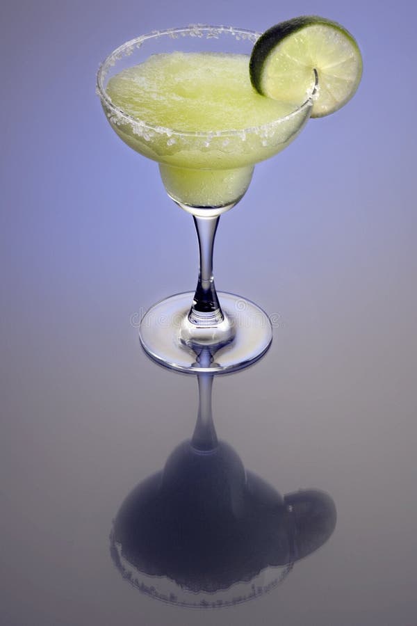 Frozen Margarita mixed drink with lime slice garnish on plain background with reflection. Frozen Margarita mixed drink with lime slice garnish on plain background with reflection