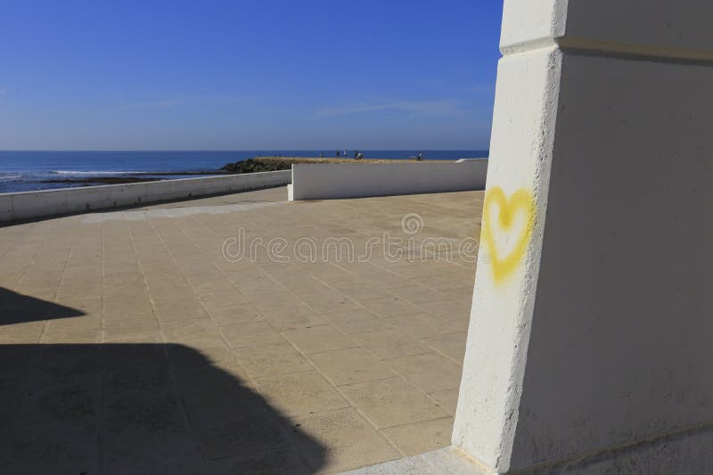 Yellow heart drawn on wall on Playa de la Costilla beach and promenade in Rota city, Cadiz, on a sunny day. Yellow heart drawn on wall on Playa de la Costilla beach and promenade in Rota city, Cadiz, on a sunny day